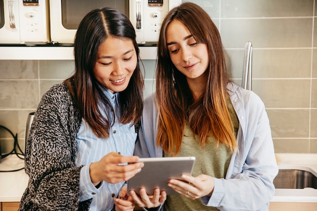 Femmes heureuses avec tablette dans la cuisine