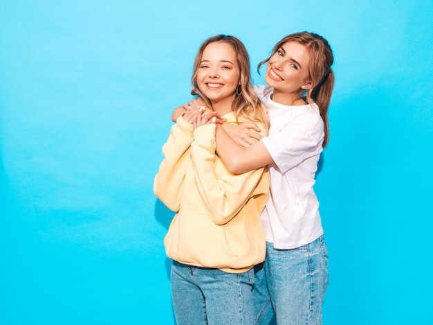 Femmes insouciantes sexy posant près du mur bleu. Modèles positifs s'amusant