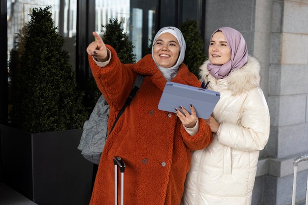 Femmes musulmanes avec hijab explorant la ville et utilisant une tablette pendant leurs vacances