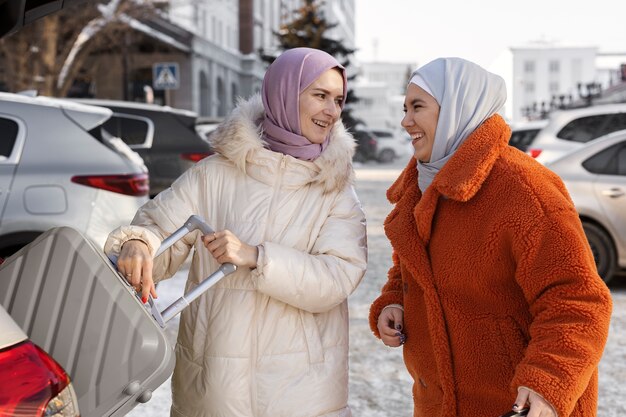 Des femmes musulmanes portant le hijab sortent leurs bagages du coffre d'une voiture pendant leurs vacances