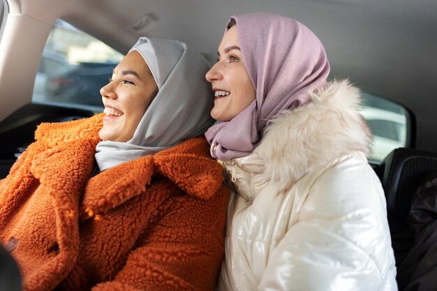 Photo gratuite femmes musulmanes souriant et explorant la ville avec une voiture tout en étant en vacances