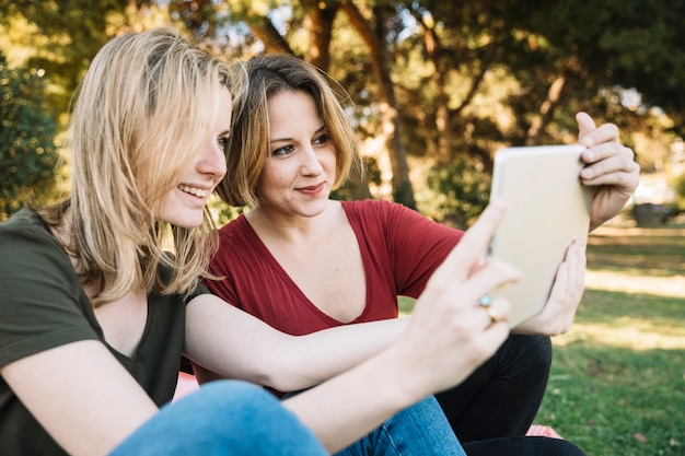 Photo gratuite femmes parcourant tablette sur pique-nique