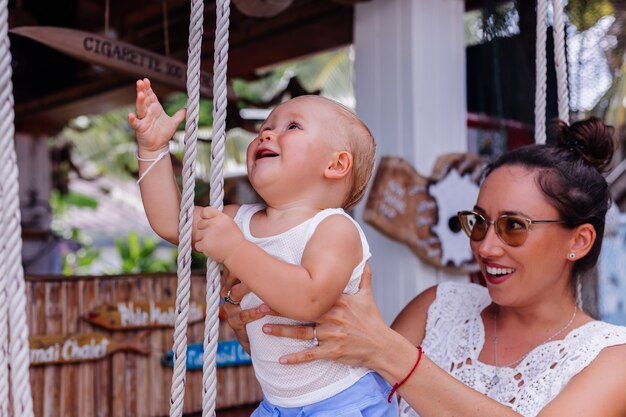 Les femmes peu rire enfant amusement balançoire famille jardin balançoire jouissance plein air mode de vie gens portrait nature enfance ensemble parc parentalité loisirs jour vacances joie happin