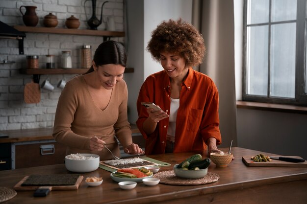 Femmes de plan moyen apprenant à faire des sushis