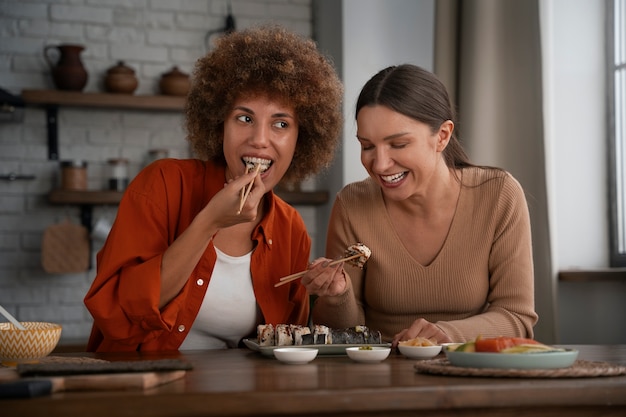 Femmes de plan moyen apprenant à faire des sushis