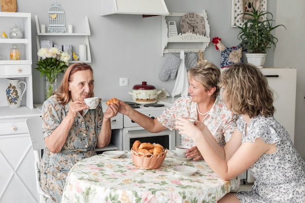 Photo gratuite femmes de plusieurs générations dégustant un croissant avec du café au petit-déjeuner