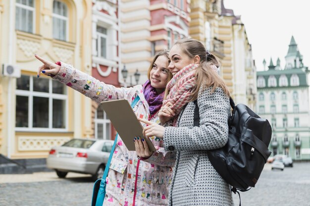 Femmes pointant loin et en utilisant une tablette