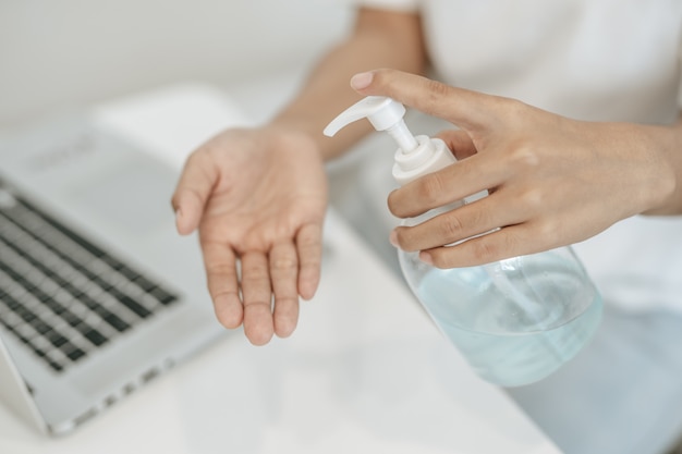 Les femmes portant des chemises blanches qui pressent le gel pour se laver les mains pour se nettoyer les mains