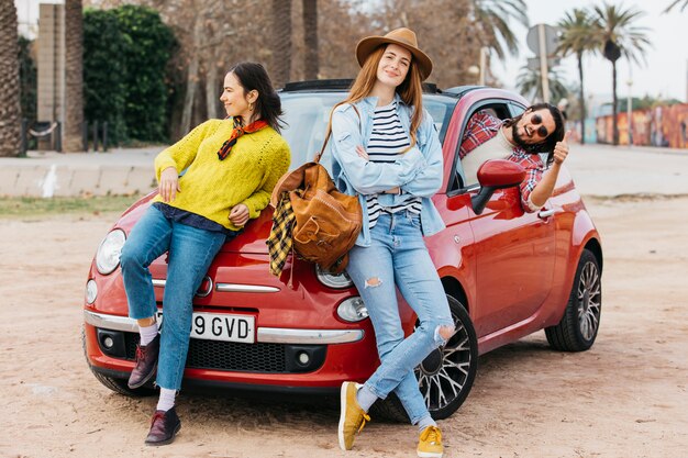 Femmes près de l&#39;homme se penchant hors de la voiture et montrant le pouce vers le haut