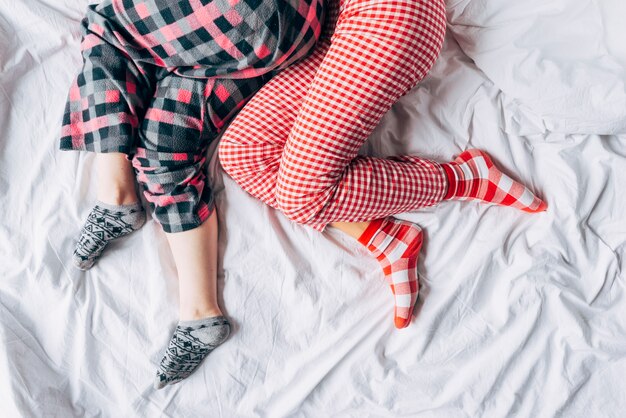 Femmes en pyjama coloré et chaussettes dormant sur le lit