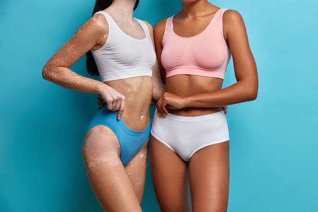 Les femmes sans visage se soucient du corps vêtues de sous-vêtements ont le ventre plat se tiennent près les unes des autres ont une peau lisse.
