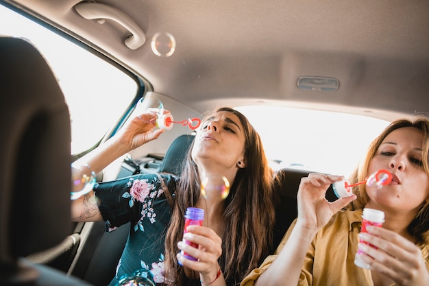 Femmes soufflant des bulles dans la voiture
