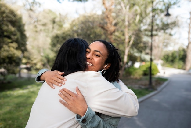 Photo gratuite femmes souriantes à coup moyen étreignant à l'extérieur