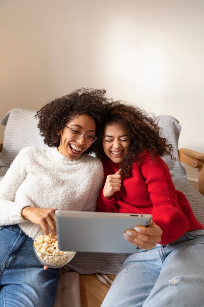 Femmes souriantes à coup moyen tenant une tablette