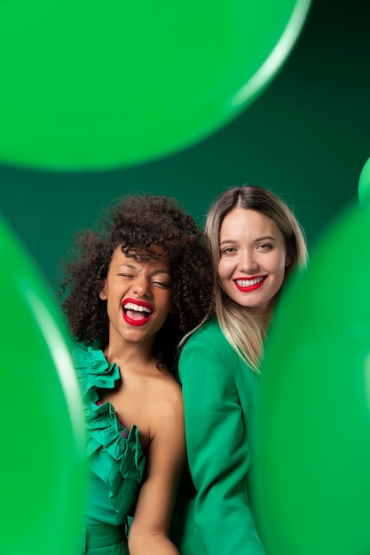 Femmes souriantes de plan moyen avec des ballons verts