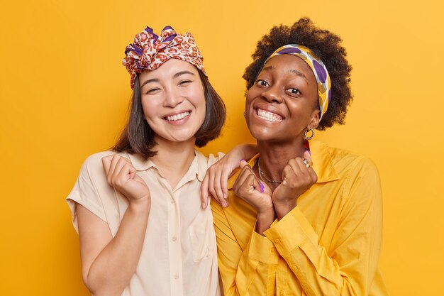 les femmes sourient largement s'amusent ensemble, heureuses d'entendre de bonnes nouvelles optimistes poser pour faire des photos. Diverses étudiantes heureuses de réussir les examens. Concept d'ethnicité et d'émotions