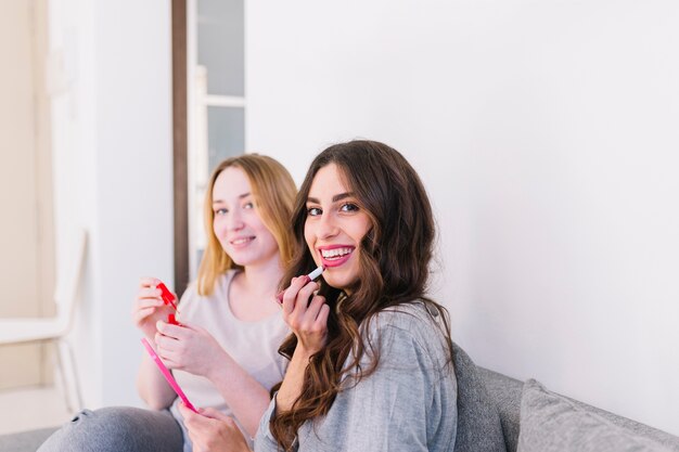 Femmes utilisant des produits cosmétiques sur le canapé