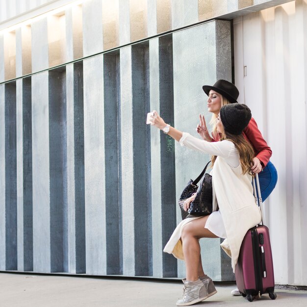 Femmes avec valise prenant selfie