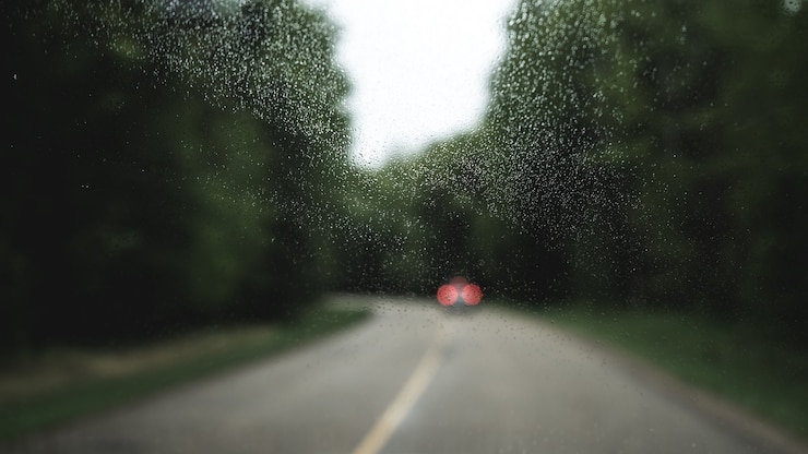 Photo gratuit fenêtre en cristal avec une vue floue d'une voiture dans une route
