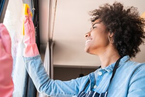 Photo gratuite fenêtre de nettoyage femme afro avec un chiffon à la maison.