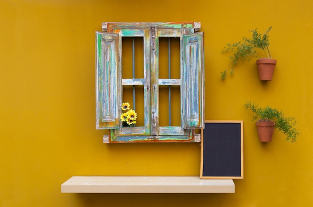 Photo gratuite fenêtre rétro décorative avec plantes sur mur jaune