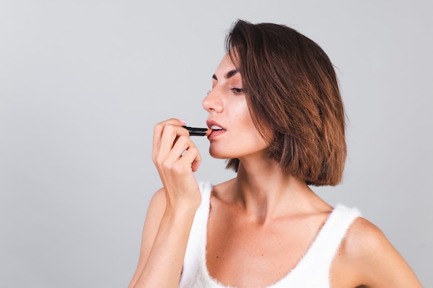 Fermer le portrait de beauté d'une femme avec du maquillage et du rouge à lèvres marron sur un mur gris