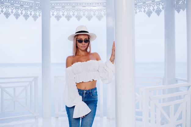 Fermer le portrait de mode en plein air de femme élégante en haut tendance blanc volumineux et chapeau de luxe classique et lunettes de soleil léopard