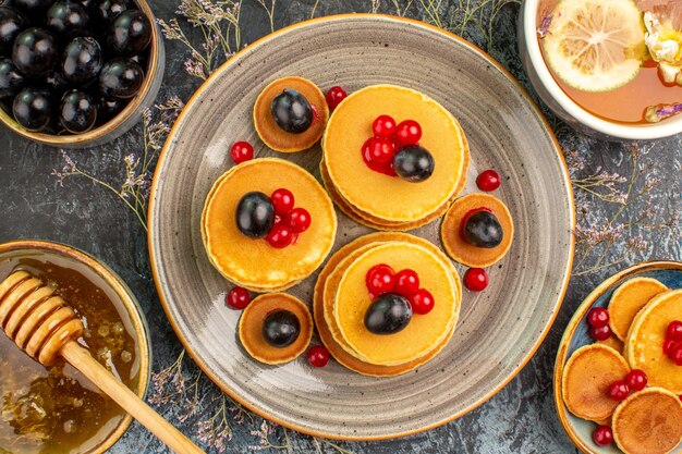 Fermer la vue du petit-déjeuner avec pile de crêpes tasse de thé au citron et miel cerise noire