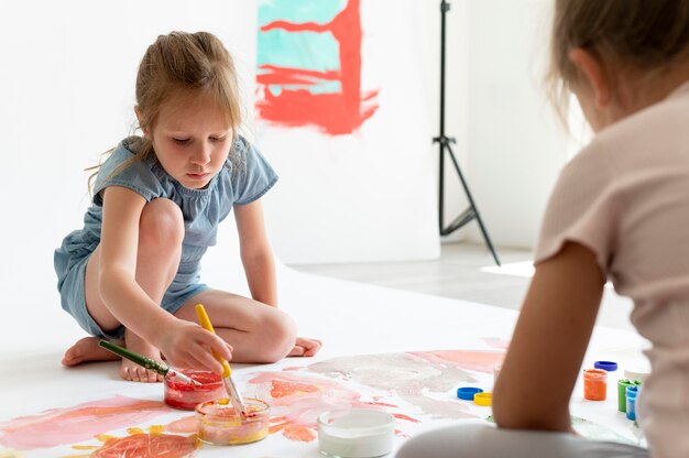 Fermez les enfants peignant ensemble à l'intérieur