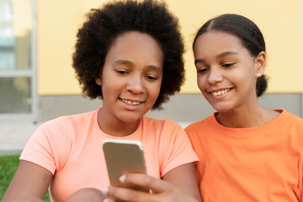 Fermez les filles souriantes avec le téléphone