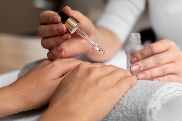 Photo gratuite fermez la main à l'aide d'huile pour les ongles