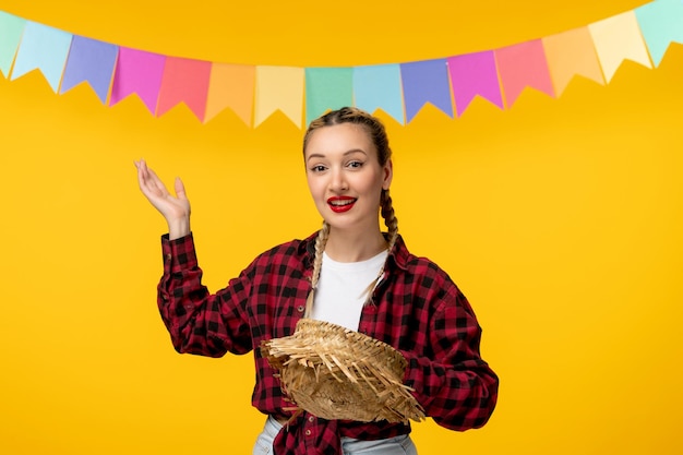 Festa junina blonde jolie fille tenant un chapeau de paille festival brésilien avec des drapeaux colorés