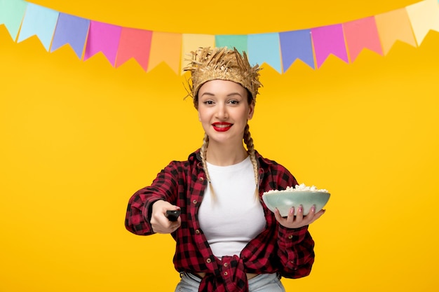 Photo gratuite festa junina jeune jolie fille au chapeau de paille festival brésilien avec des drapeaux colorés avec télécommande tv