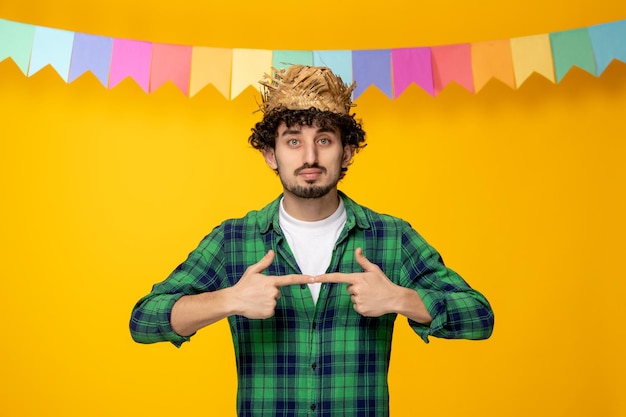 Photo gratuite festa junina jeune mec mignon en chapeau de paille et drapeaux colorés festival brésilien et doigts ensemble