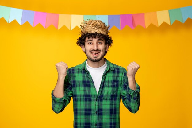 Festa junina jeune mec mignon en chapeau de paille et festival brésilien de drapeaux colorés excité