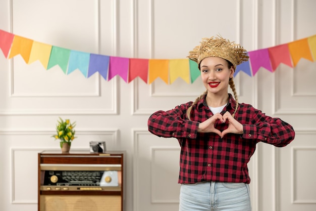 Festa junina jolie fille au chapeau de paille au milieu de l'été brésilien avec radio rétro drapeaux colorés coeur mains