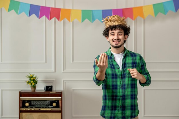 Festa junina mignon jeune homme au chapeau de paille avec radio rétro et drapeaux colorés invitant avec les mains