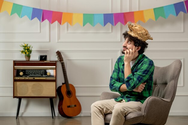 Festa junina mignon jeune homme au chapeau de paille avec radio rétro et drapeaux colorés pensant