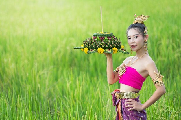 Festival Loy Krathong; femme en tenue traditionnelle thaïlandaise tenant flottant décoré