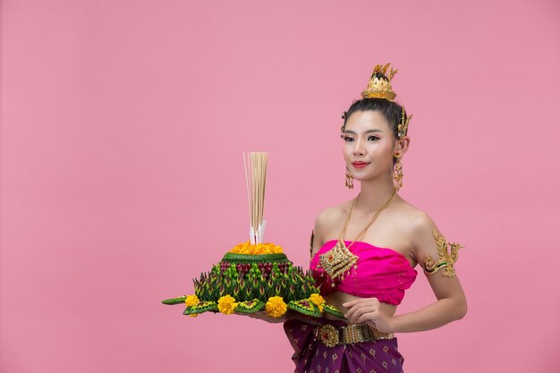 Festival Loy Krathong; femme en tenue traditionnelle thaïlandaise tenant flottant décoré