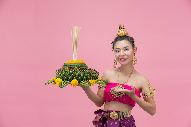 Festival Loy Krathong; femme en tenue traditionnelle thaïlandaise tenant flottant décoré