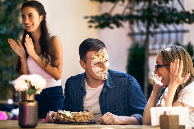 Fête de célébration d'un anniversaire pour un garçon adulte avec un gâteau et une blague de visage