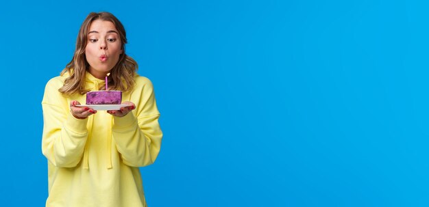 Fête de célébration et concept de style de vie stupide jolie femme blonde européenne en sweat à capuche jaune faisant voeu