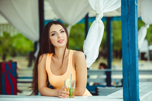Fête d'été. Sexy jeune femme aux cheveux longs, boire un cocktail au bar de la plage.