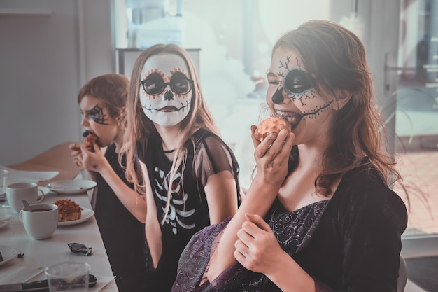 Photo gratuite fête d'halloween en cours - les enfants sont assis à côté de la table et ont de délicieuses friandises.