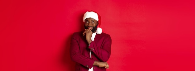 Photo gratuite fête de noël et concept de vacances homme afro-américain souriant faisant des plans pour le nouvel an à la recherche de toi