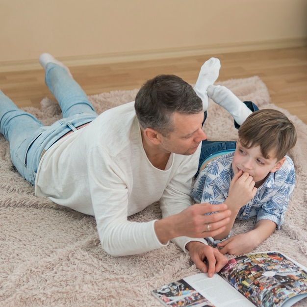 Photo gratuite fête des pères papa et fils lisant une bande dessinée haute vue