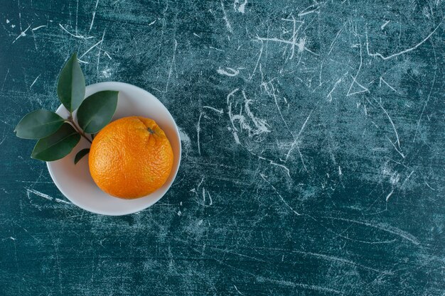 Feuille et mandarine dans un bol , sur la table en marbre.