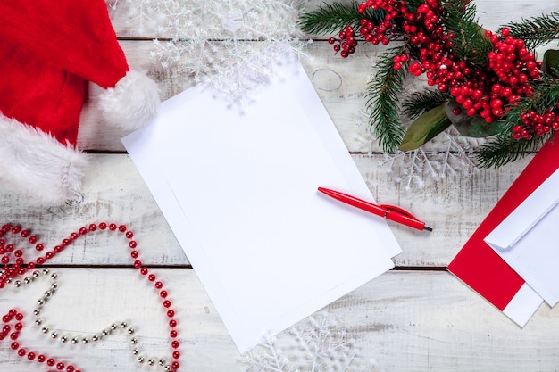 Feuille de papier vierge sur table en bois avec un stylo et des décorations de Noël