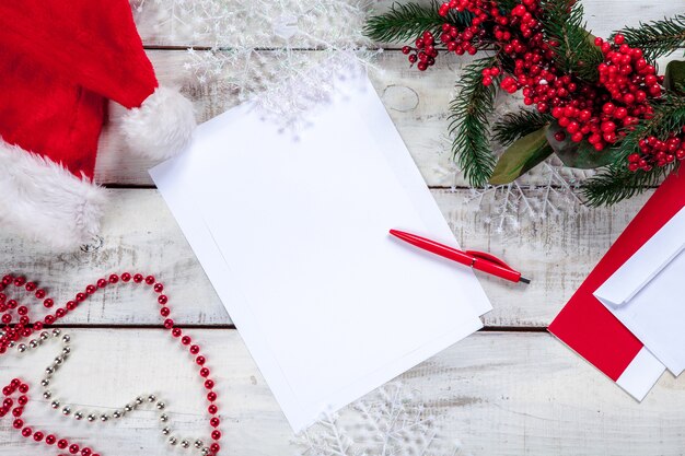 Feuille de papier vierge sur table en bois avec un stylo et des décorations de Noël